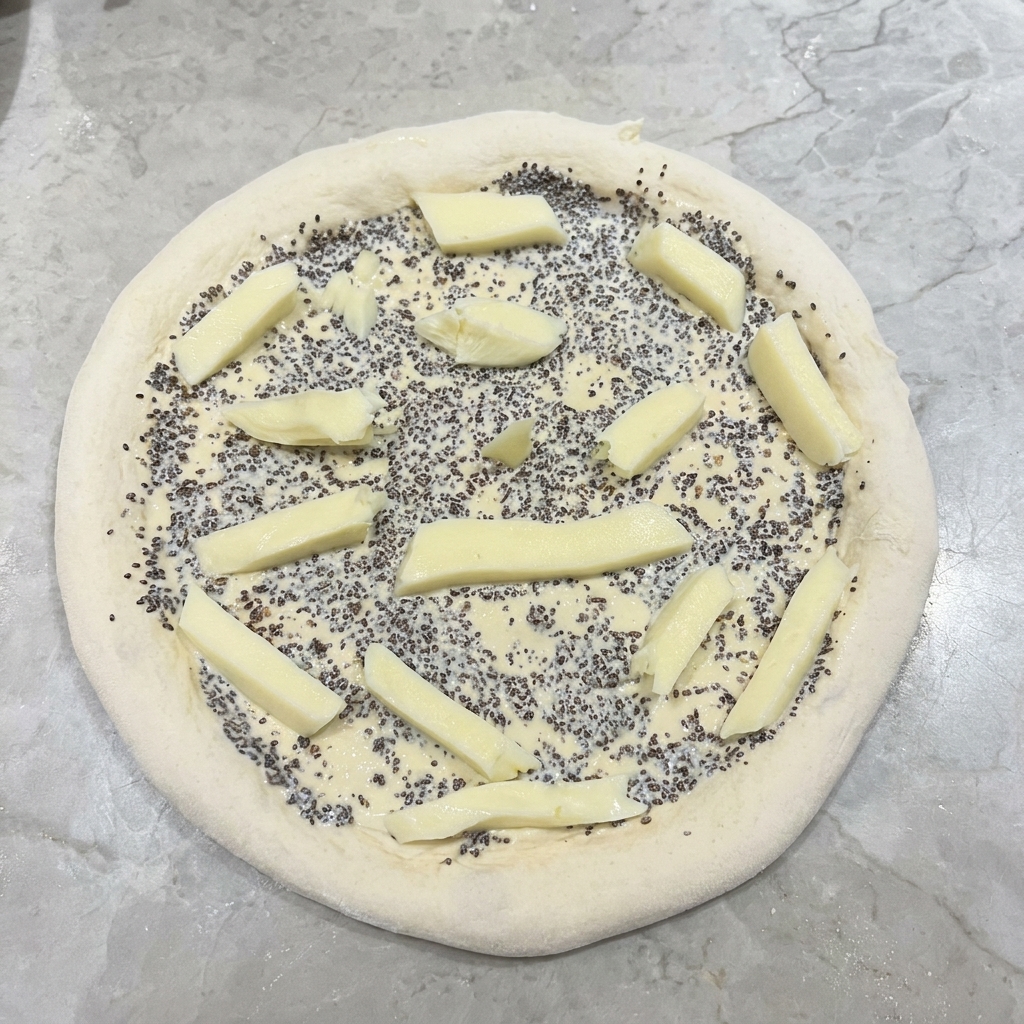Bâtonnets de mozzarella blanche fraîche disposés sur une pâte à pizza recouverte de sauce à la truffe.