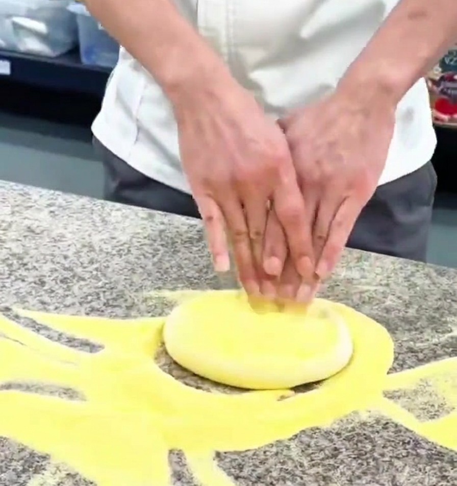 Gros plan sur des mains pressant une boule de pâte à pizza sur un plan de travail fariné.