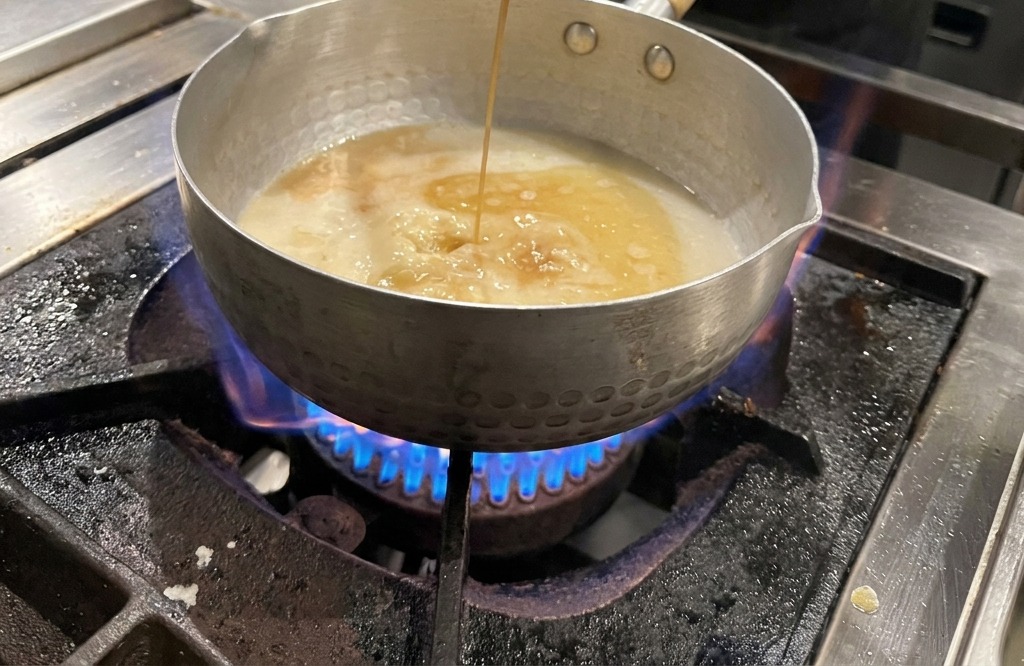 Sauce soja versée à la louche dans la casserole de bouillon.