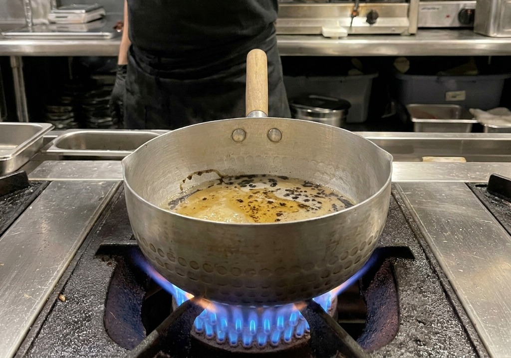 Gouttes dhuile noire intense flottant sur la sauce brune dans la casserole.