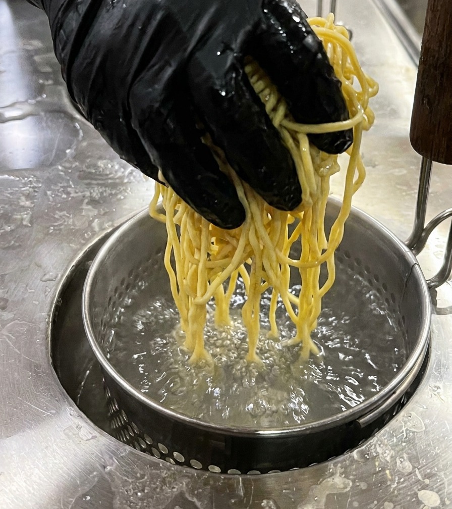 Un panier à nouilles rempli de ramen plongé dans leau bouillante.