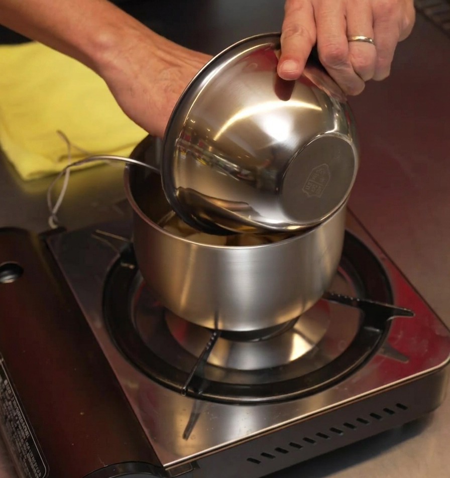Des gousses dail frais pelées versées dun bol en inox dans une petite casserole.