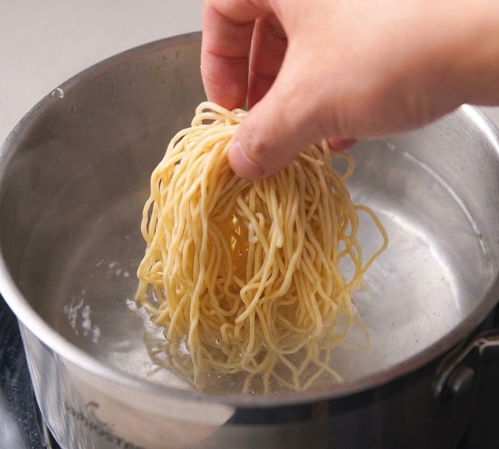 Une grande casserole remplie deau sur le feu avec de petites bulles se formant au fond de la paroi.