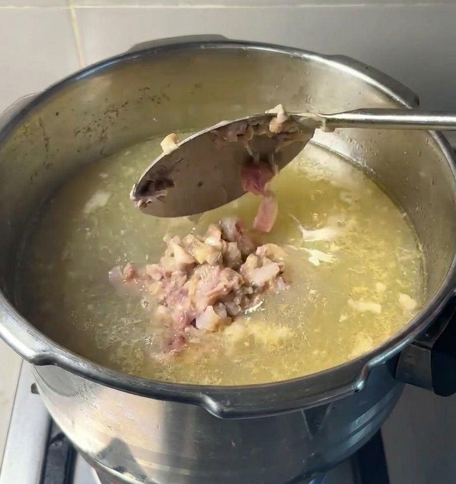 Une grande cuillère déposant la pâte de viande et de moelle dans le bouillon clair qui mijote.