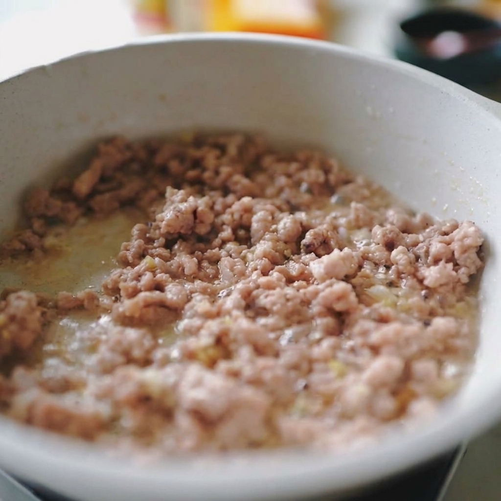 Mélange de porc haché et doignons blancs émincés sautant ensemble dans une poêle claire.