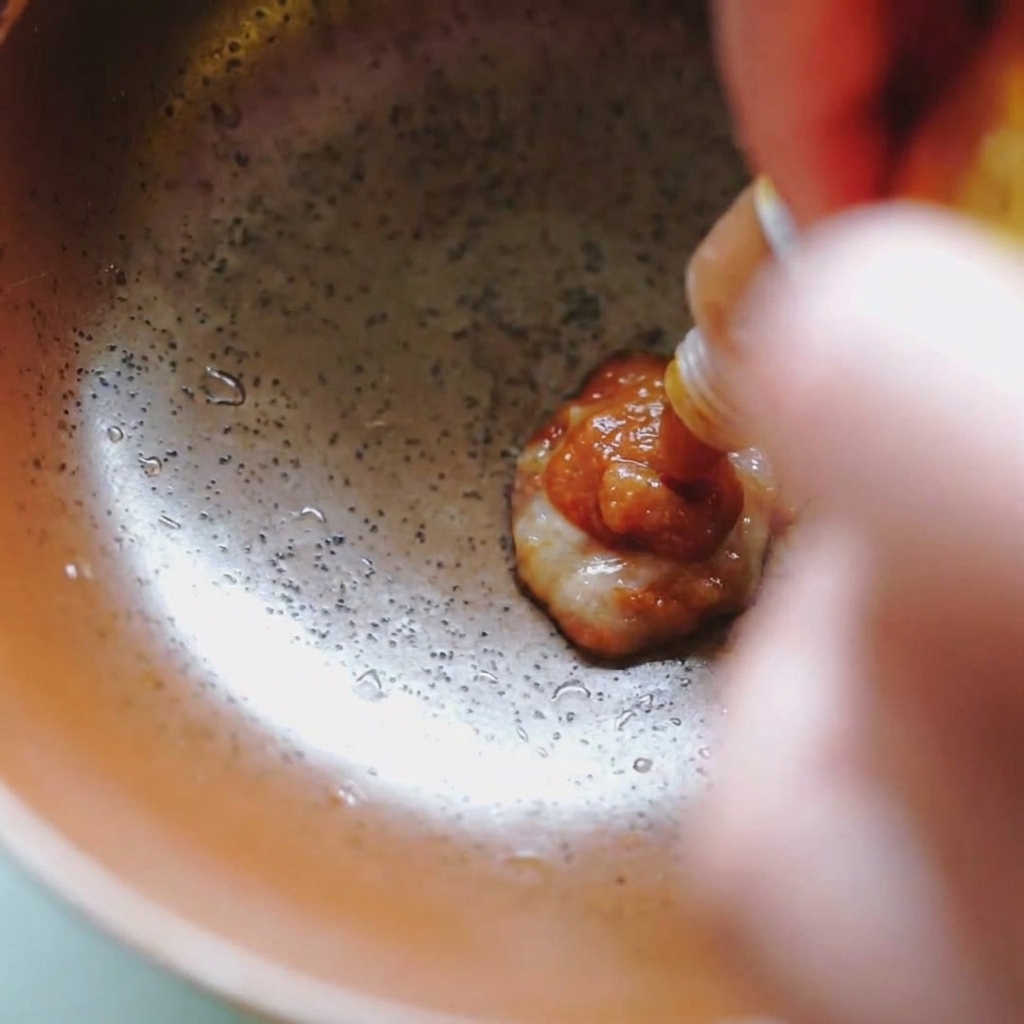 Pâte de miso brune épaisse pressée dun sachet dans un bol en céramique.