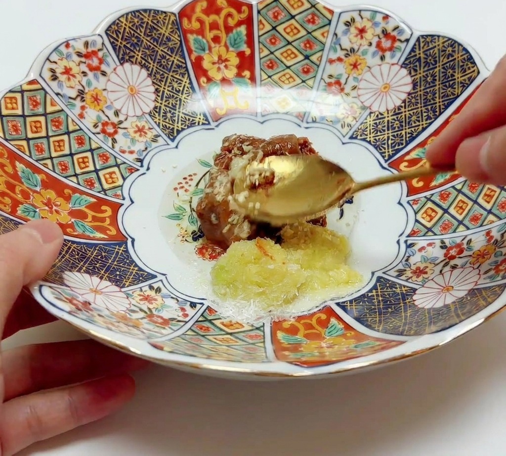 Une cuillère dorée mélangeant la pâte de miso avec les aromates et lhuile dans un grand bol.
