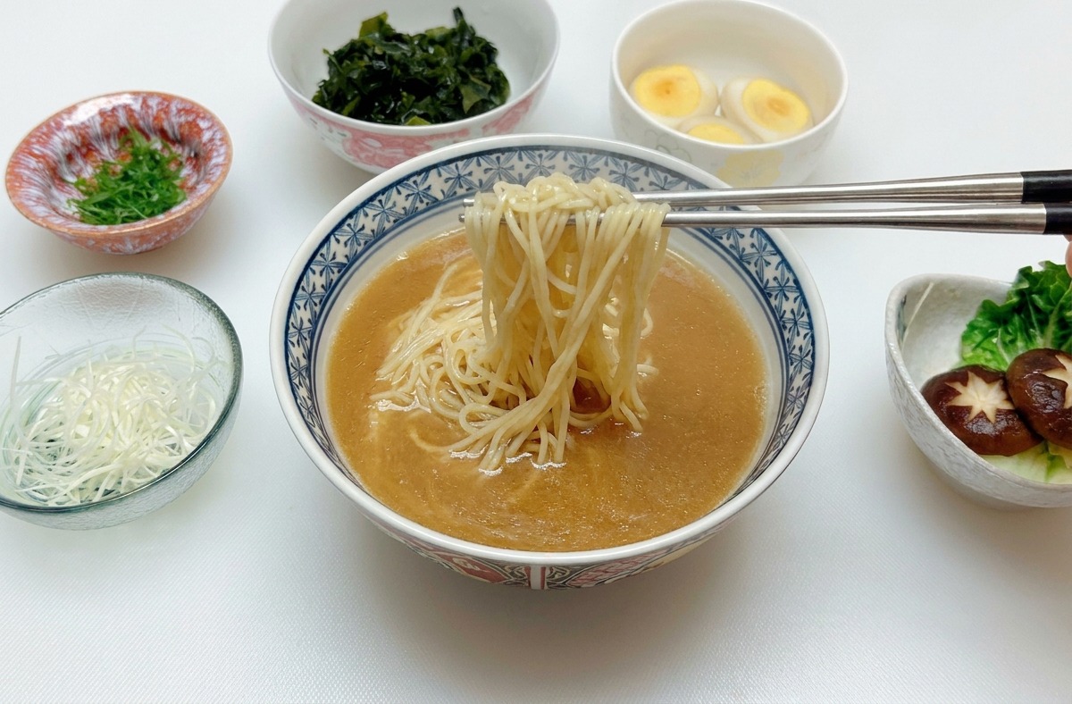 Des baguettes en argent soulevant et centrant les nouilles dans le bouillon miso.