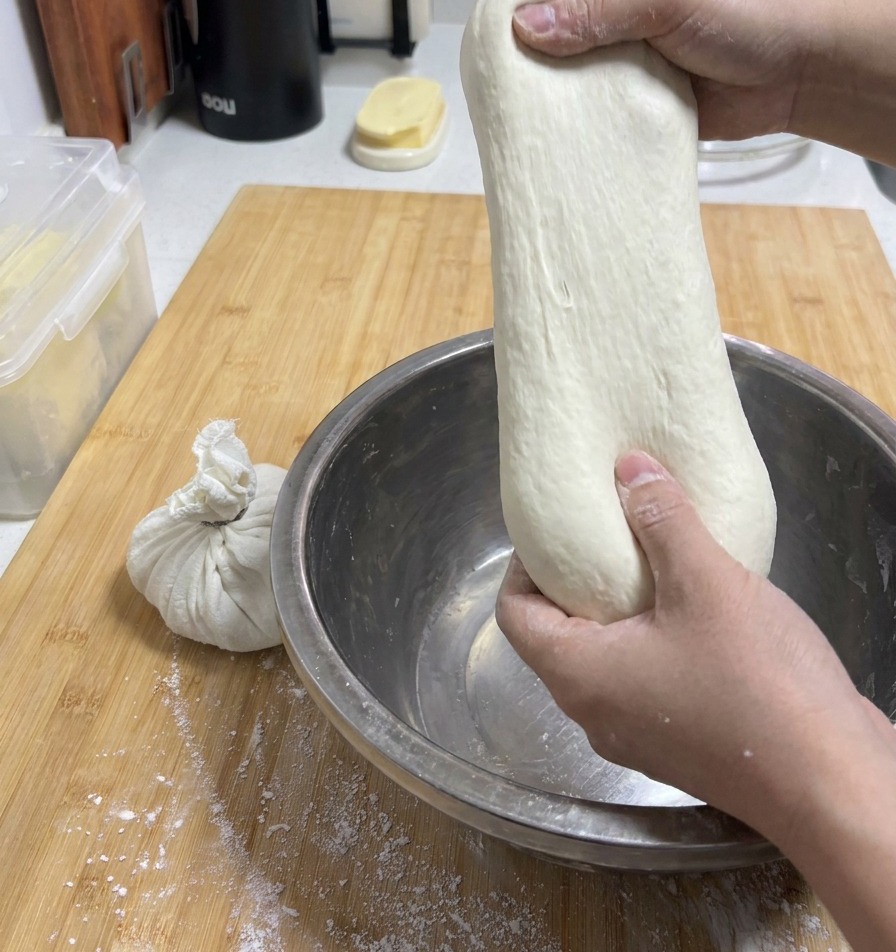 Mains étirant un morceau de pâte souple vers le haut pour montrer son incroyable extensibilité sans se rompre.