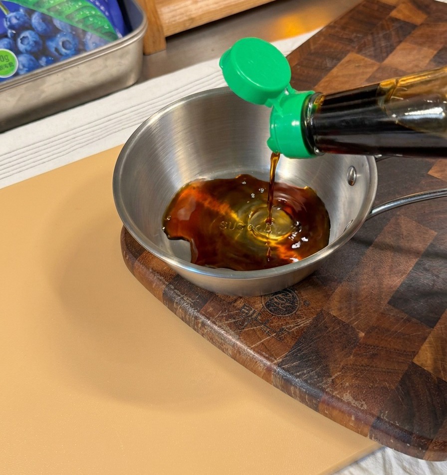 Sauce soja noire versée dune bouteille au bouchon vert dans un petit bol en inox.