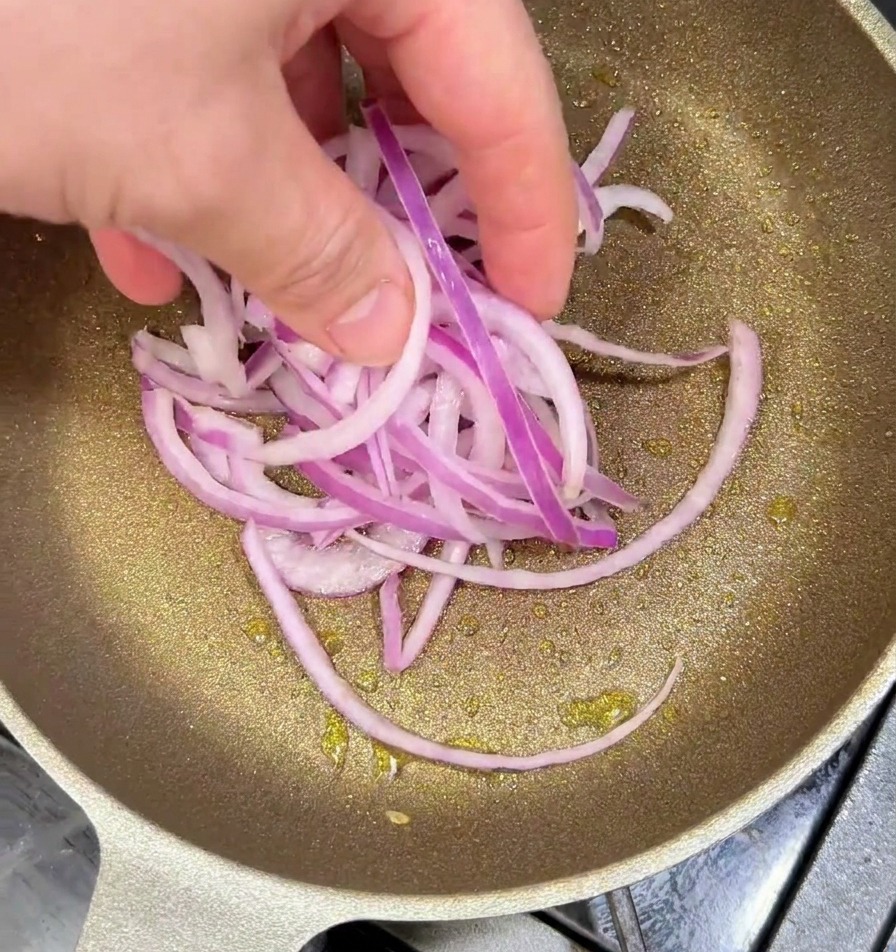 Oignons rouges émincés sautant dans une poêle chaude avec un filet dhuile.