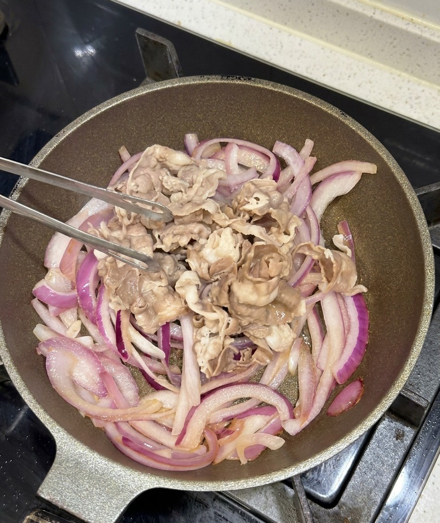 Tranches de bœuf blanchies ajoutées aux oignons caramélisés dans la poêle.