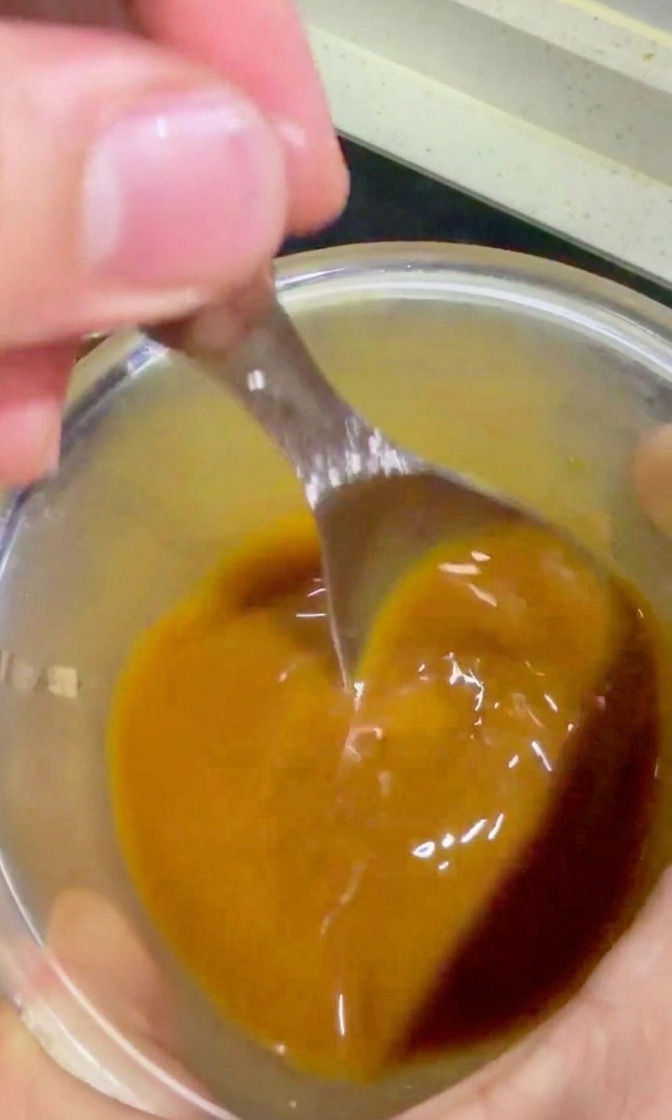 Sauce teriyaki dorée versée à la cuillère sur le bœuf et les oignons dans la poêle.