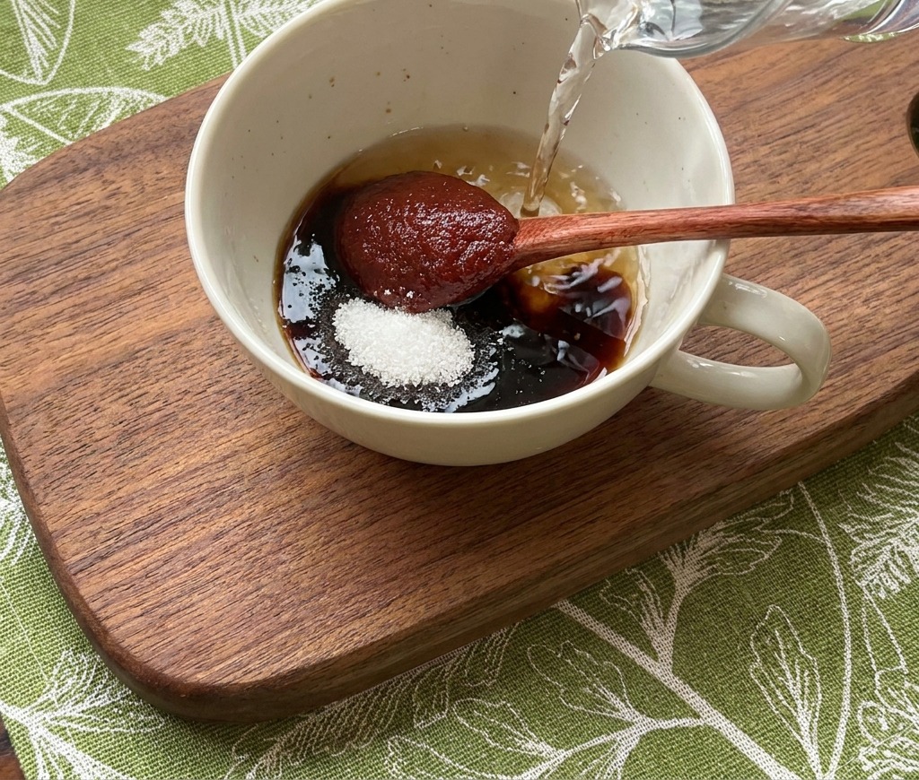 De leau claire versée dun pichet dans un bol rempli dingrédients de sauce rouges et sombres.