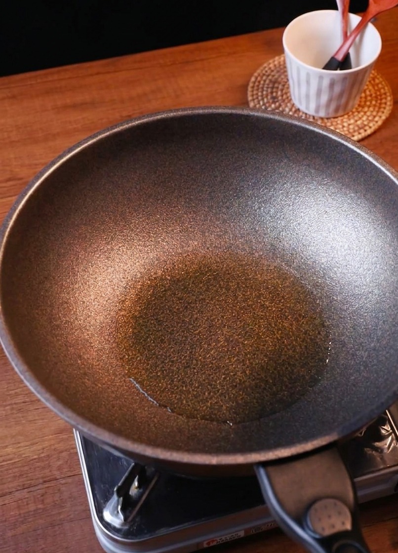 Des oignons fraîchement émincés et du kimchi haché ajoutés dans une poêle chaude.
