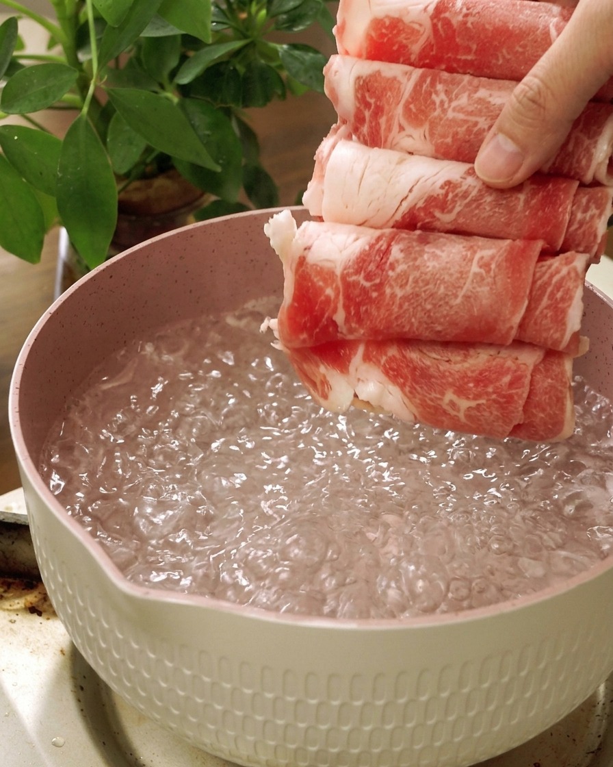 Fines tranches de bœuf cru plongées dans une casserole deau bouillante.