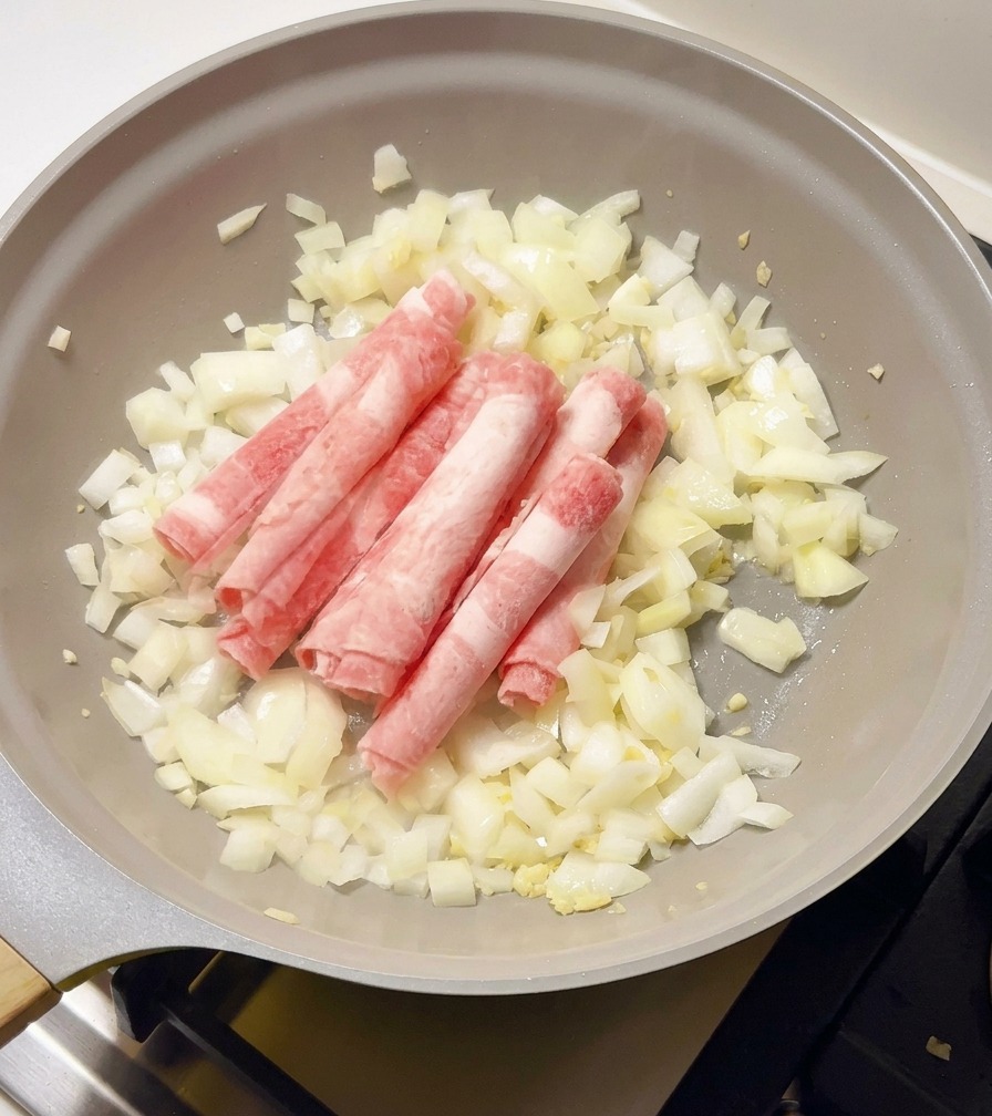 Rouleaux de bœuf cru encore congelés ajoutés dans la poêle avec les oignons.