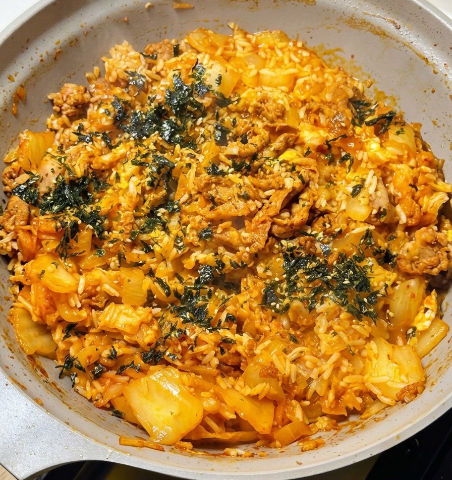 Main saupoudrant des paillettes dalgues vertes sur le riz sauté fumant.