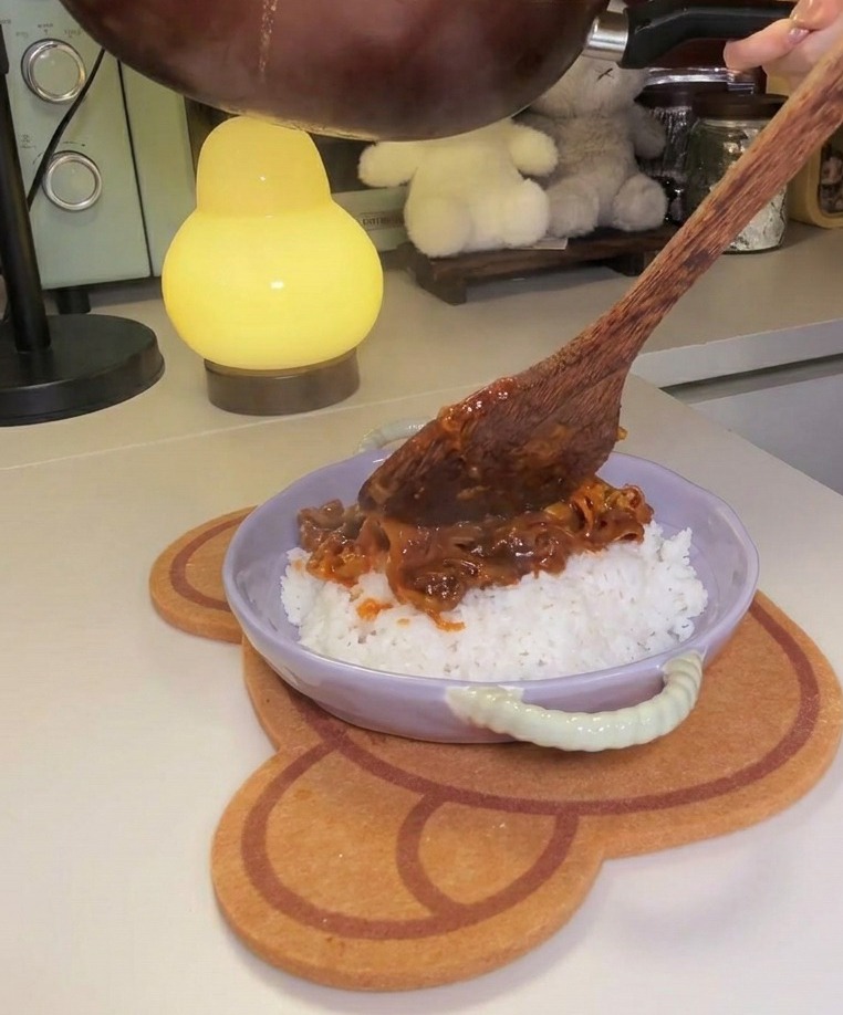 Mélange de bœuf et kimchi versé sur un dôme de riz blanc dans un bol couleur lavande.