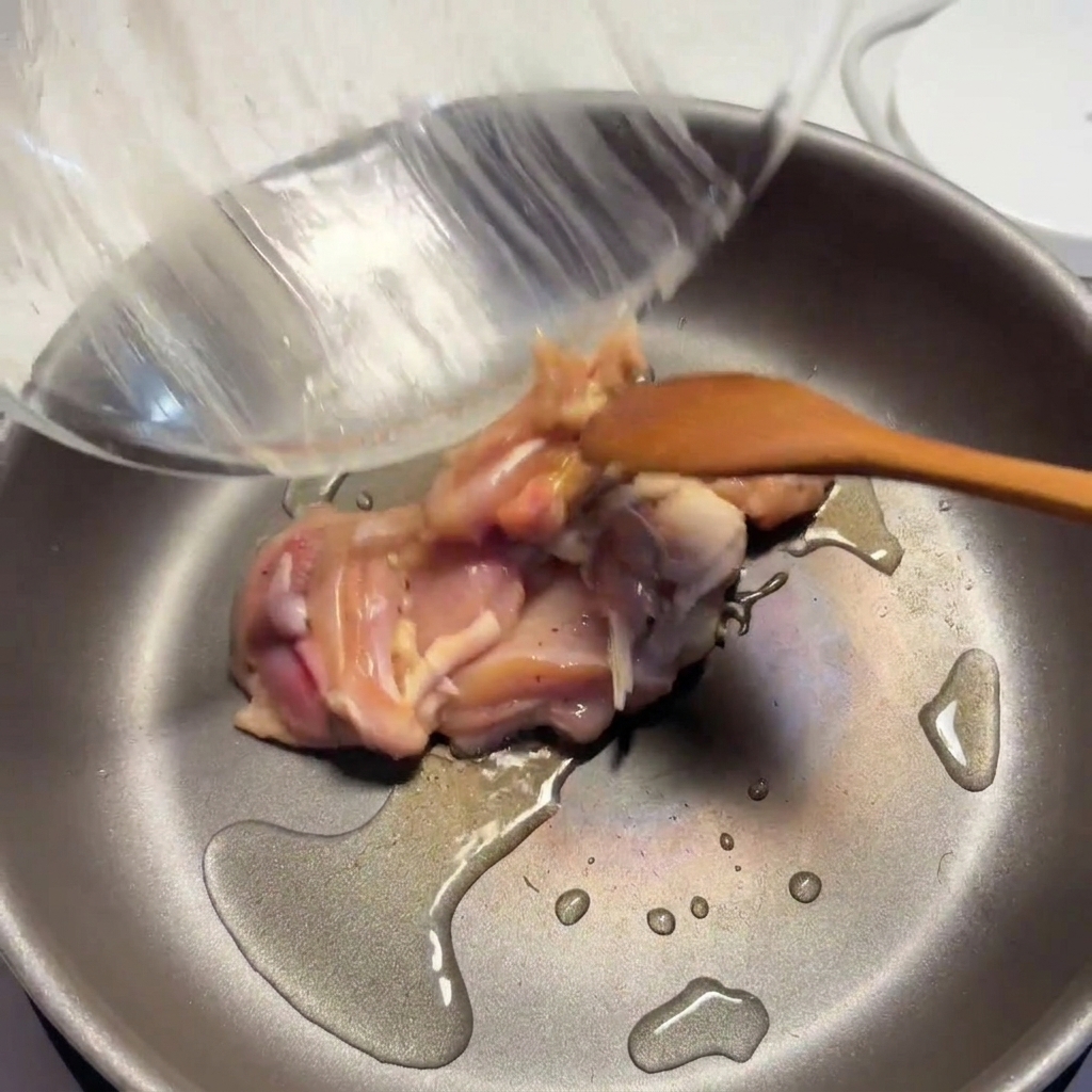 Morceaux de poulet assaisonnés cuisant dans une poêle chaude avec de lhuile, avec les surfaces qui commencent à dorer.