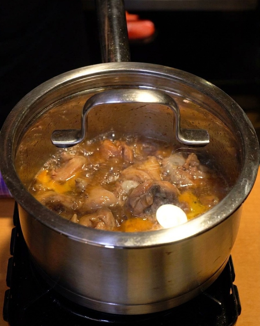 Une casserole en inox avec un couvercle en verre, de la vapeur et du liquide bouillonnant visibles à travers la vitre.