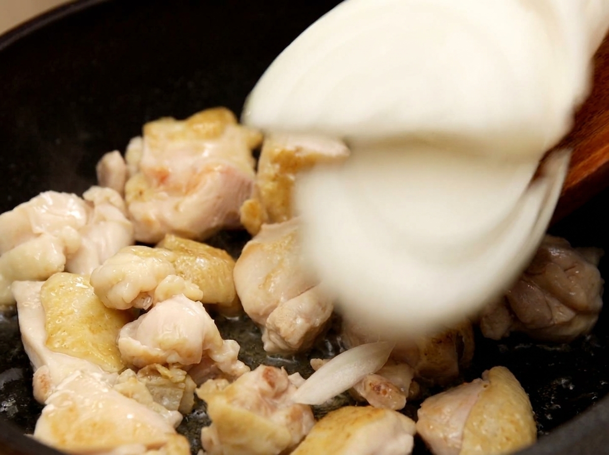 Ajout des oignons émincés dans la poêle avec le poulet doré.