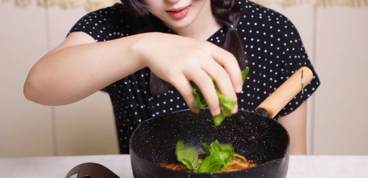 Légumes verts frais saupoudrés à la main dans une poêle de poulet, doignons et dœufs dans une sauce dashi.