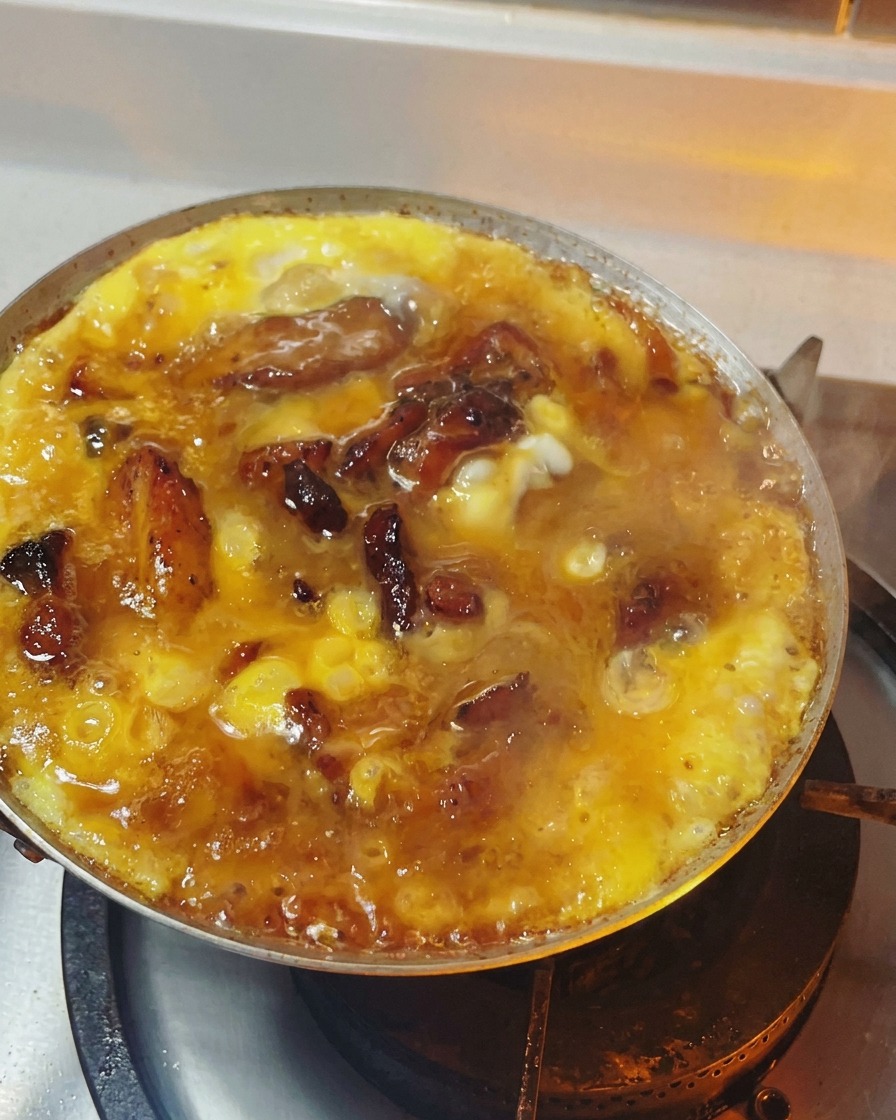 Oyakodon dans une poêle avec des œufs à la texture semi-solide et brillante sur un lit de poulet.