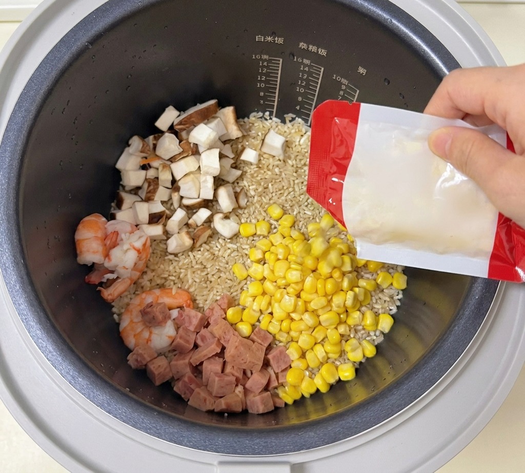 Des grains de maïs doux versés dun sachet dans un cuiseur à riz contenant du riz, des crevettes, des champignons et du jambon.