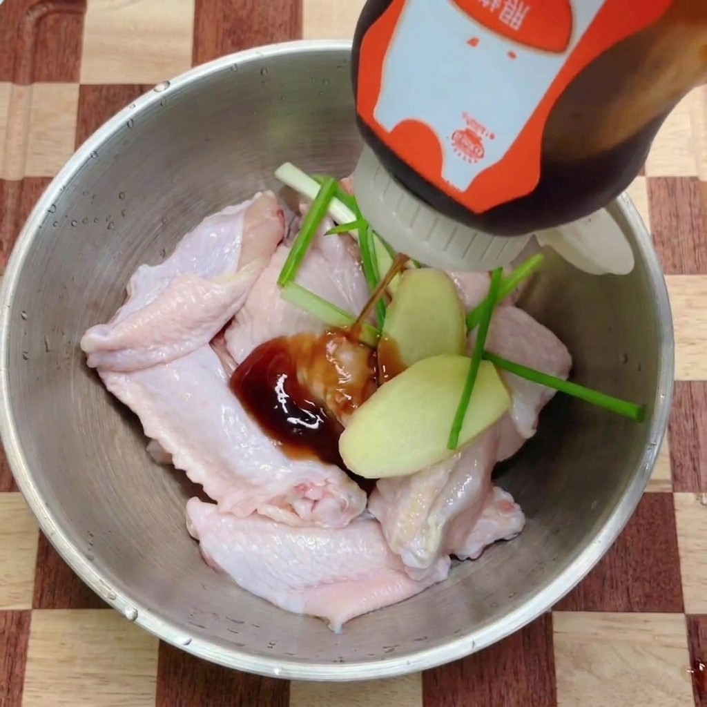 De la sauce teriyaki sombre versée sur un bol dailes de poulet garnies daromates frais.