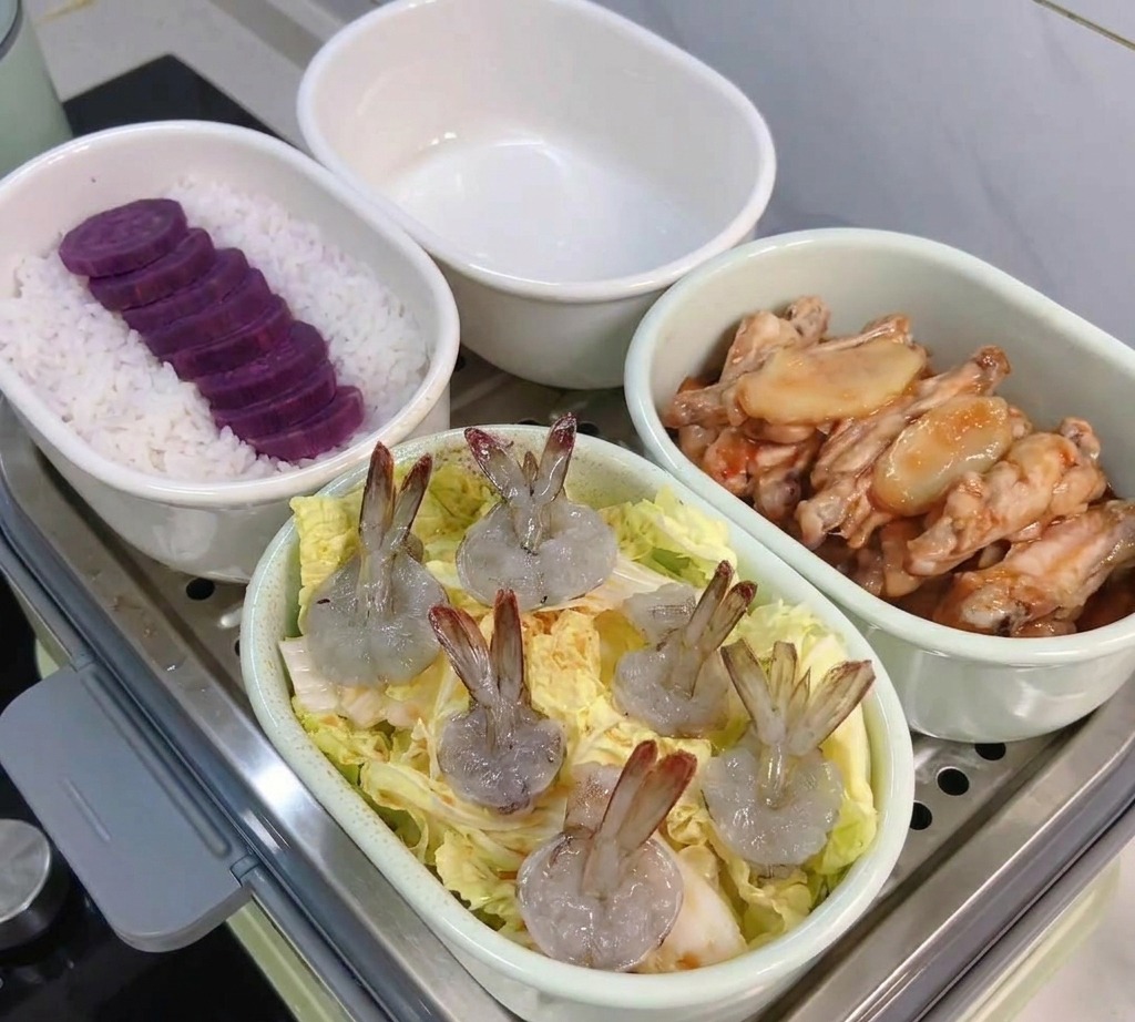 Un plat ovale contenant des feuilles de chou surmontées de crevettes décortiquées prêtes pour le cuiseur vapeur.