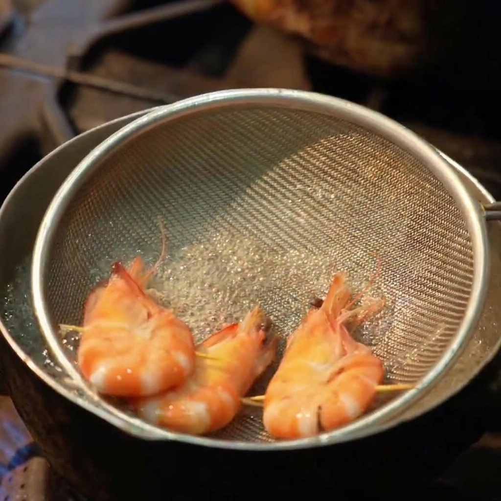 Trois crevettes entières bouillies dans une passoire plate à lintérieur dune casserole deau bouillante.