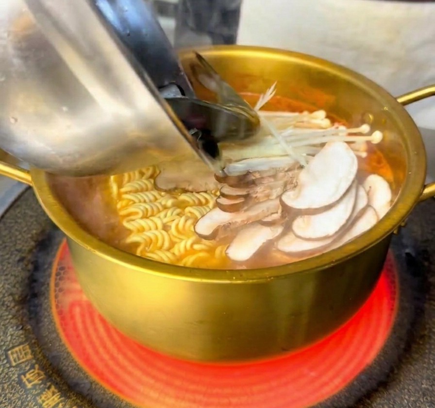 Des crevettes fraîches et des moules versées dun bol en inox dans la marmite bouillante.