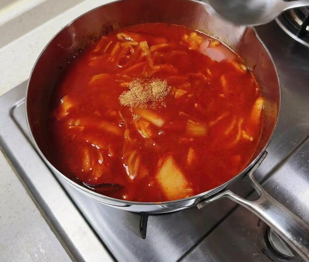 Un petit tas de poudre de bouillon de bœuf au centre dune marmite de bouillon rouge épicé frémissant.