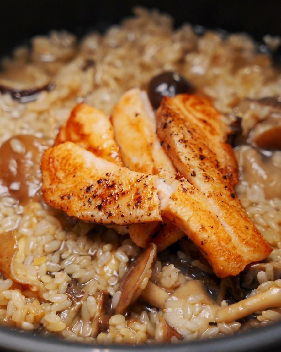 Trois morceaux de filets de saumon dorés posés sur le riz et les champignons non cuits dans un cuiseur à riz.
