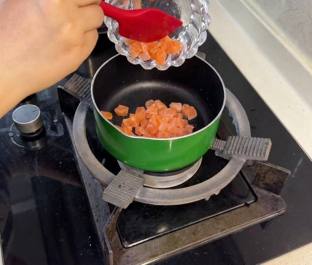 Cubes de saumon marinés sautant dans une poêle verte jusquà ce quils deviennent opaques.