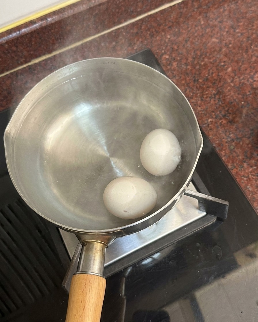 Deux œufs blancs au fond dune casserole remplie deau chaude, de la vapeur séchappant de la surface.