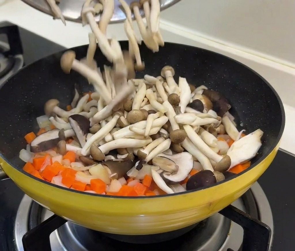 Champignons frais et petits pois versés dun bol dans une poêle contenant des carottes et des oignons sautés.