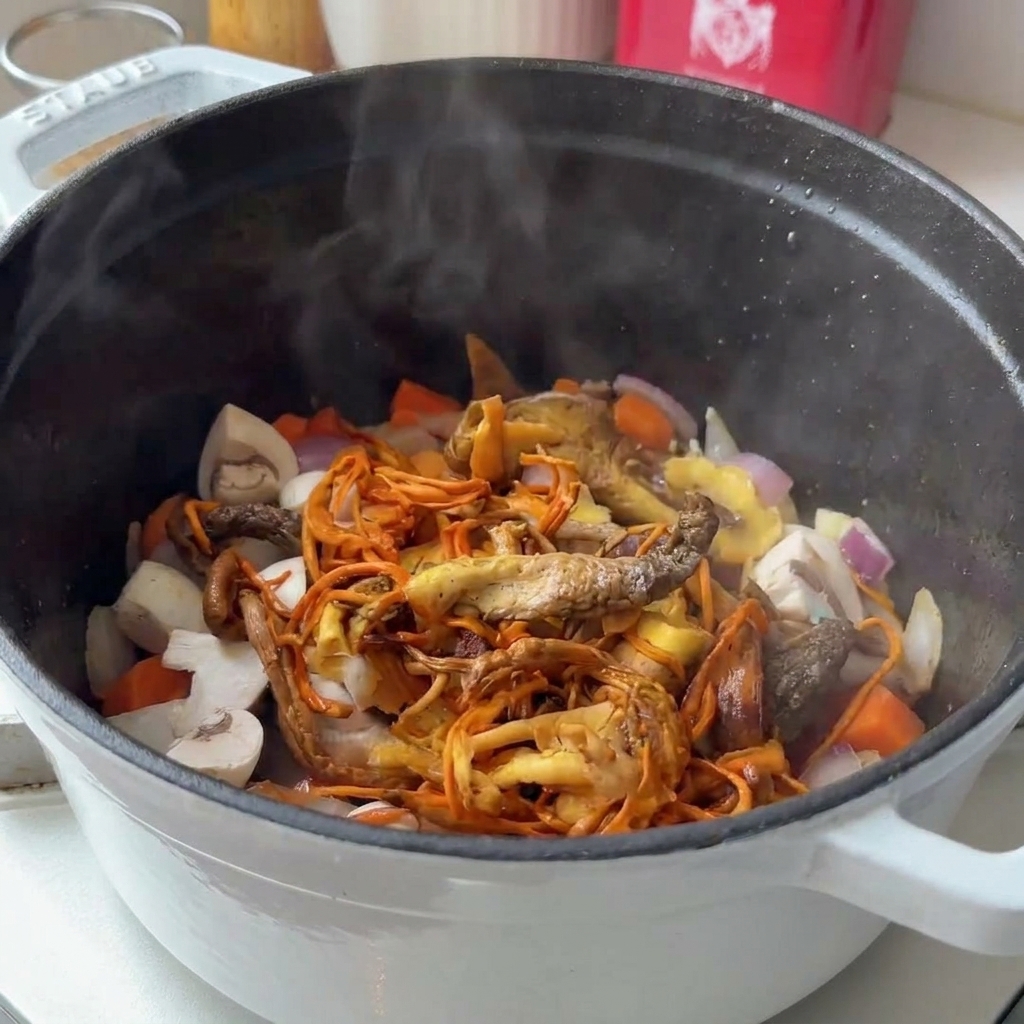 Divers champignons frais et réhydratés ajoutés dans une marmite de légumes fumants.