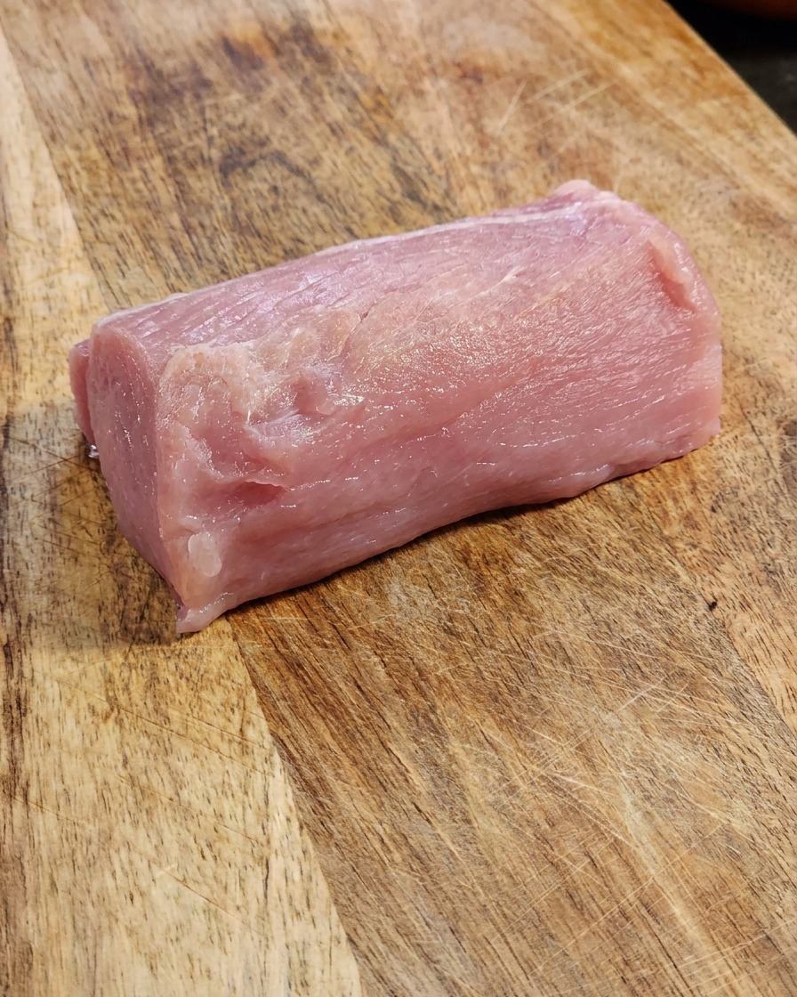 Tranche de longe de porc fraîche sur une planche à découper en bois