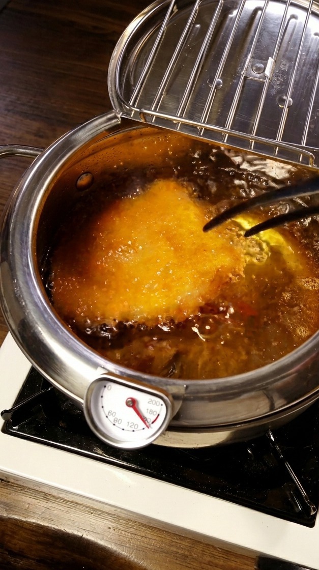 Escalope de porc panée en friture dans lhuile chaude avec un thermomètre