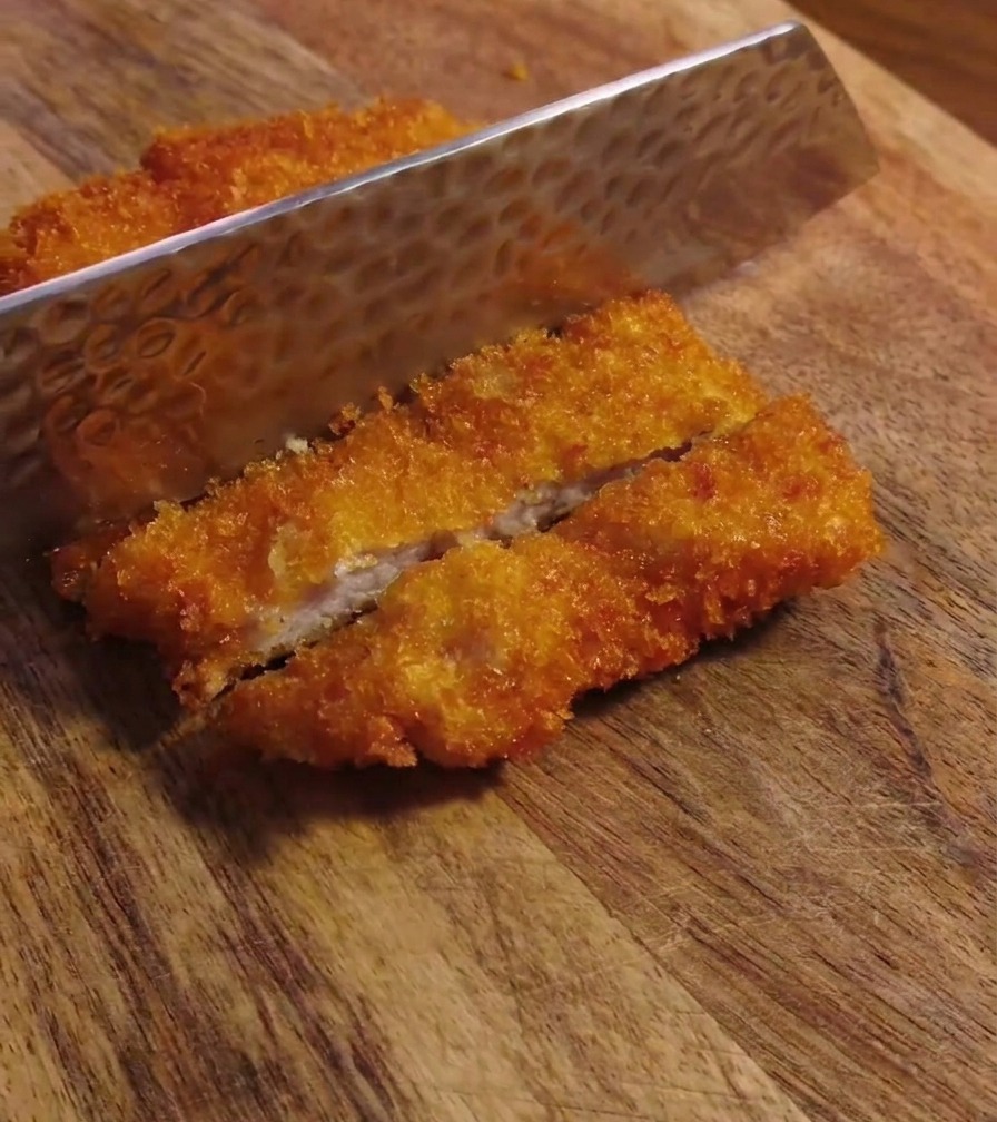 Couteau tranchant découpant le porc frit croustillant sur une planche
