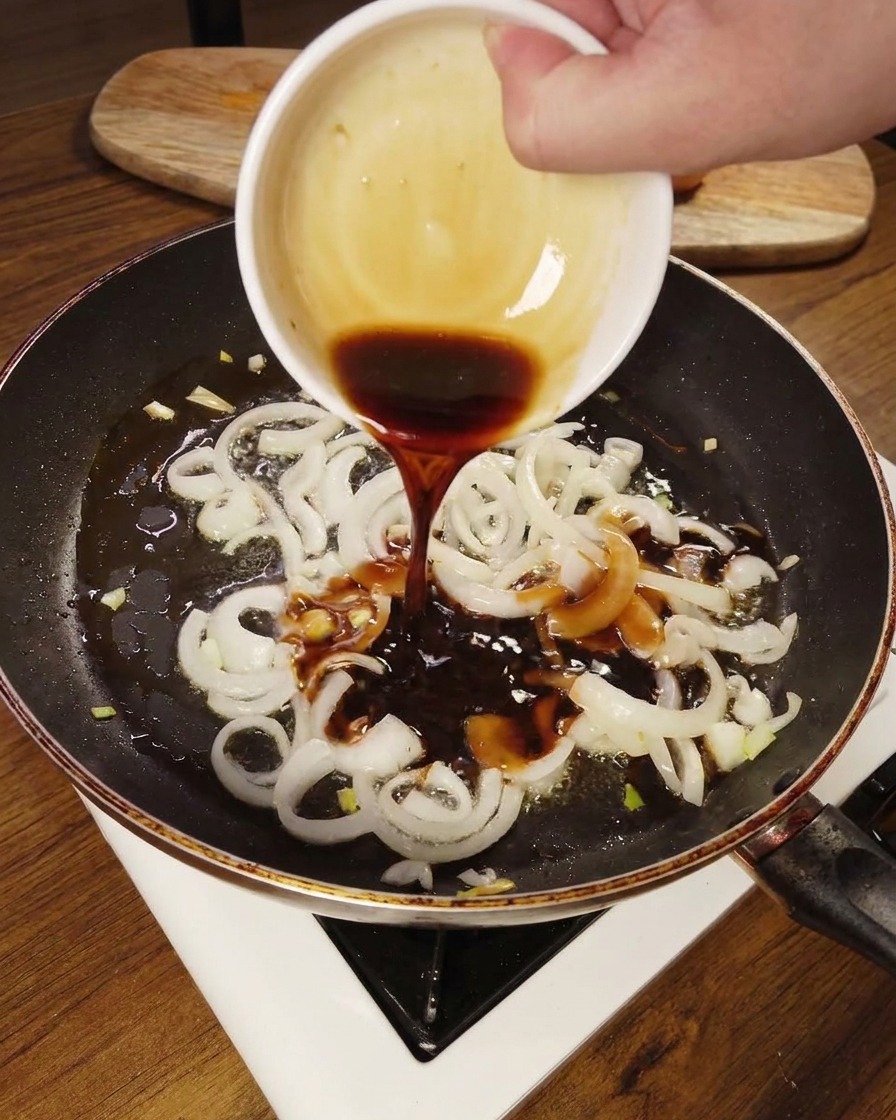 Sauce versée sur les oignons ramollis dans la poêle