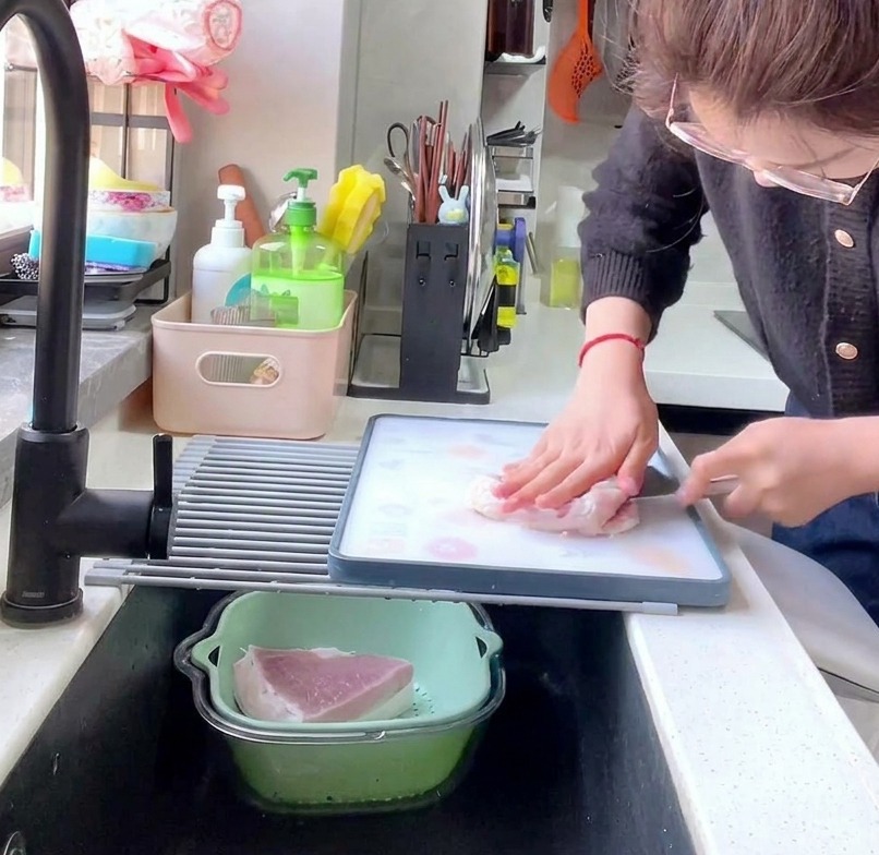 Vue latérale dune personne utilisant un couperet pour détailler une longe de porc crue en tranches épaisses denviron 1 cm sur une planche à découper.