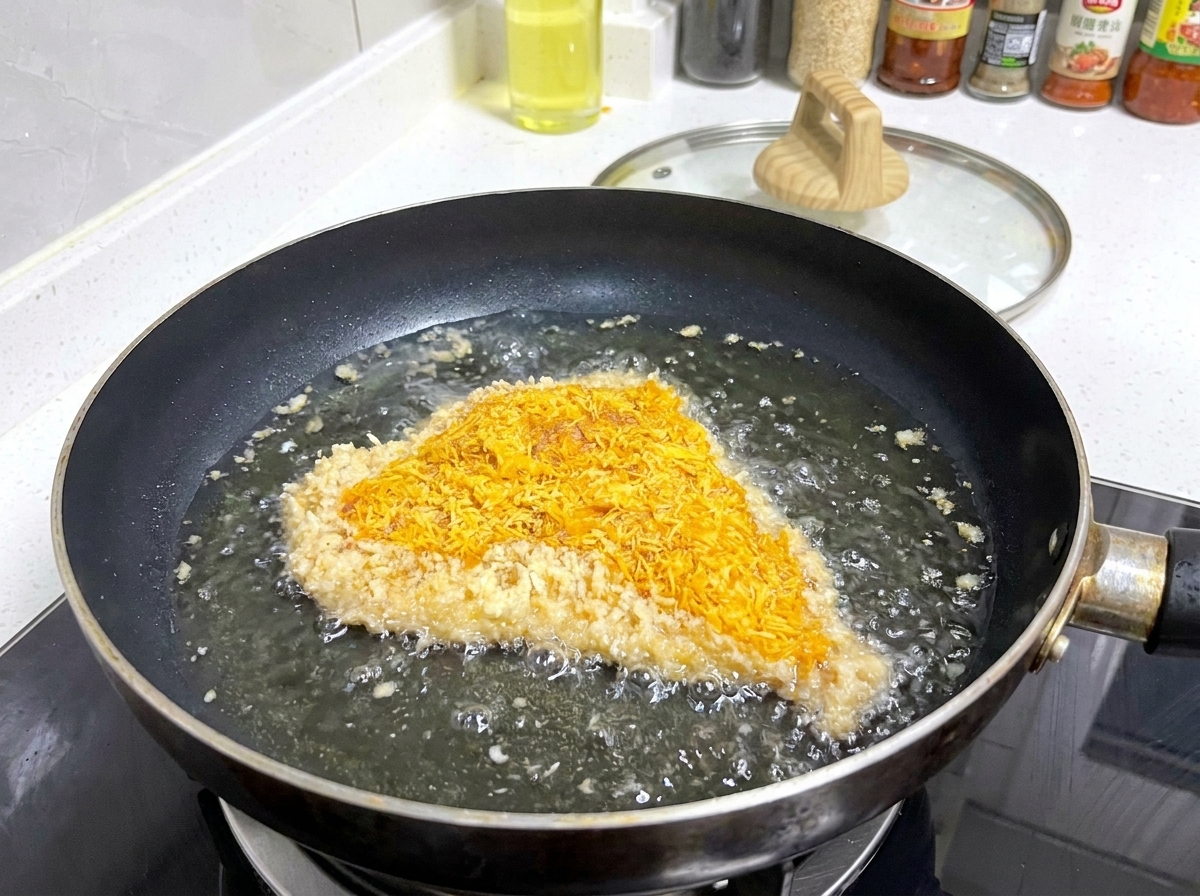 Une côtelette de porc panée grésille dans une poêle peu profonde remplie dhuile chaude, avec des bulles se formant sur les bords de la panure.