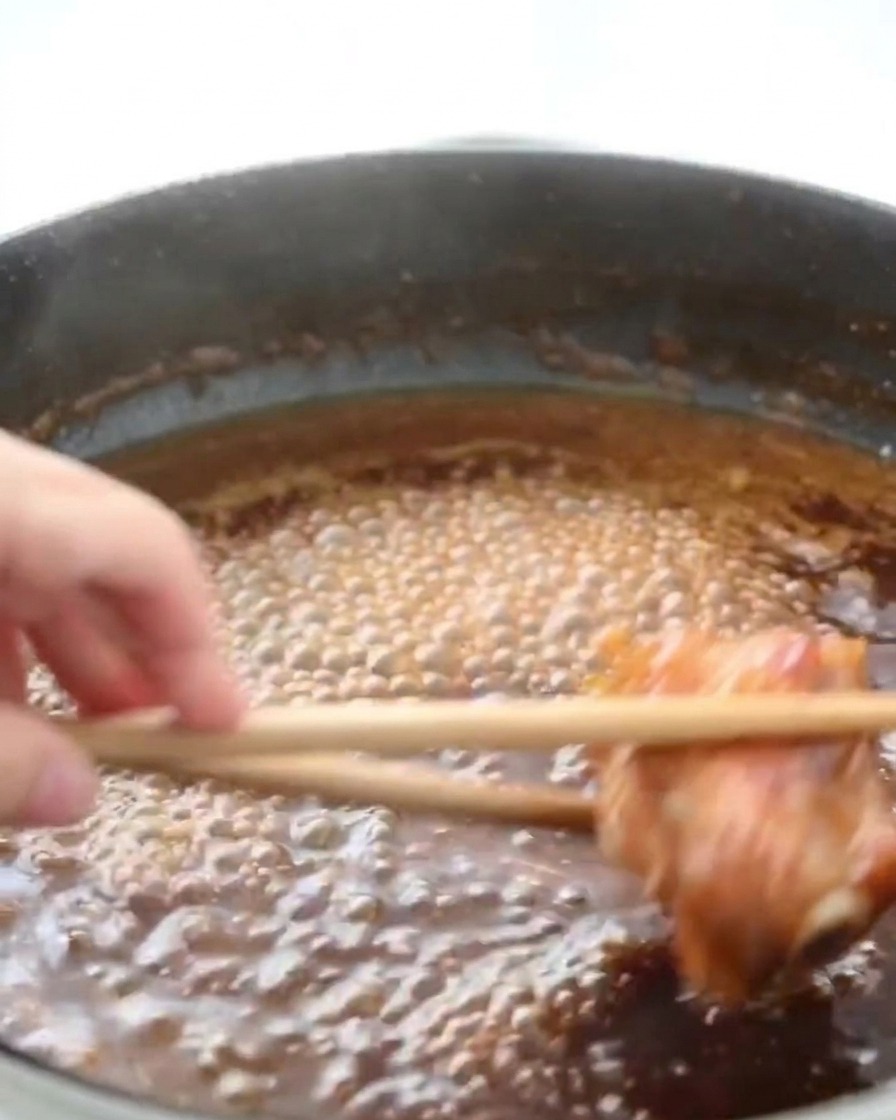 Poulet mijotant dans une sauce brune bouillonnante avec de la vapeur séchappant de la poêle.