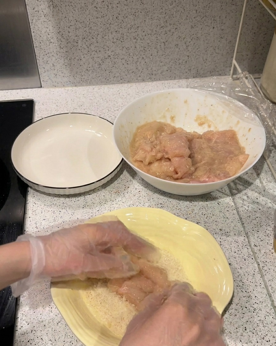 Un filet de poulet mariné pressé dans une assiette remplie de chapelure Panko claire.