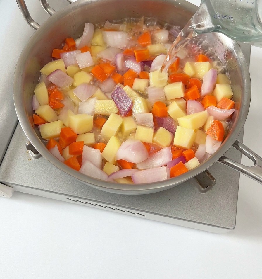 Eau versée sur les légumes dans la poêle pour créer le bouillon.