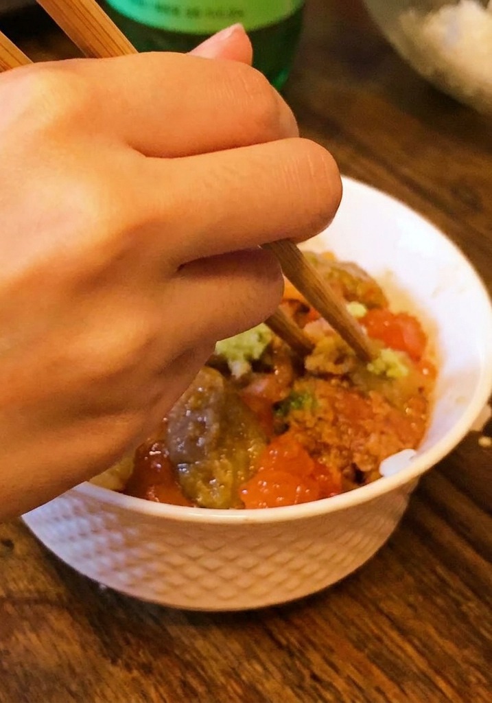 Une main posant une petite noisette de wasabi au centre dun bol doursin et dœufs de saumon.