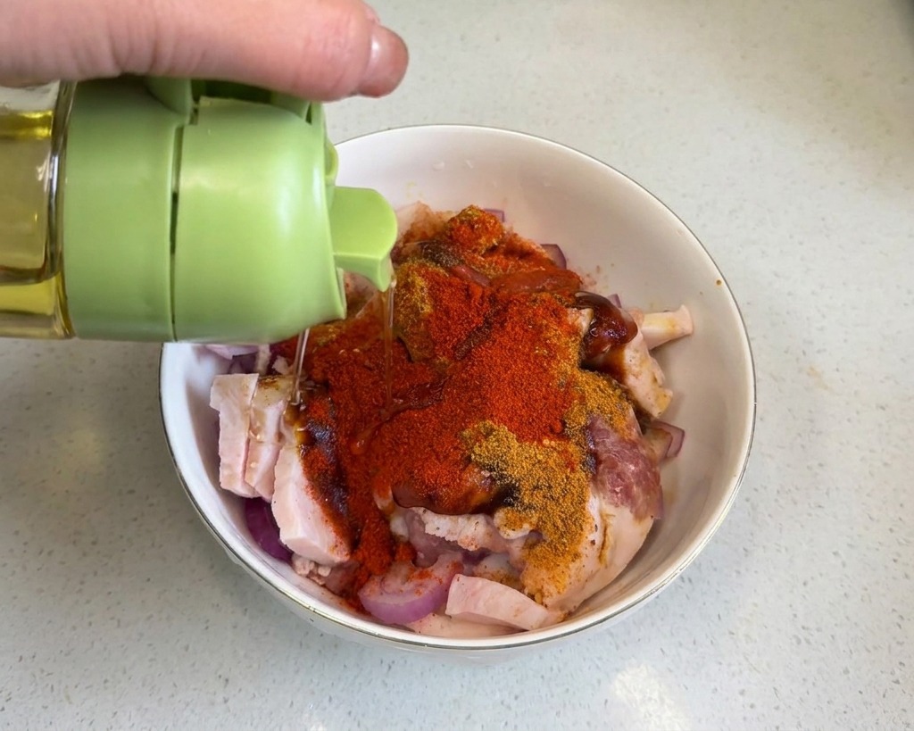 De lhuile de cuisson versée sur la poitrine de porc recouverte de poudres dépices rouges.